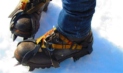 Mountaineering boots with step-in crampons on packed snow, for steep spring snow hiking and alpine terrain