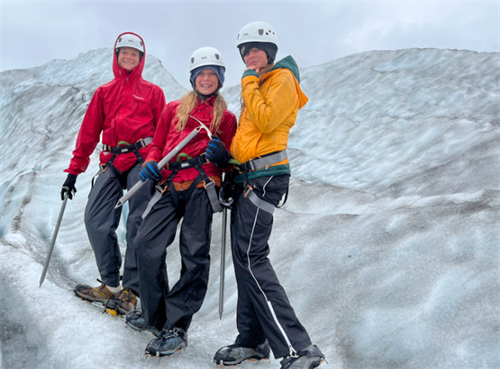 Group of hikers with full crampons, ice axes, and climbing gear on a glacier, demonstrating advanced spring snow hiking equipment
