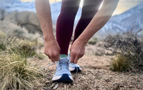 Hiker tying the laces of trail running shoes before a fastpacking trip in mountainous terrain