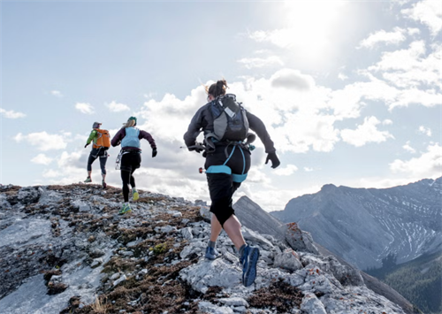 Fastpackers wearing trail running shoes moving quickly along a rocky alpine ridge