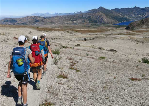 Group of fastpackers hiking on an arid mountain trail, wearing trail runners and lightweight gear