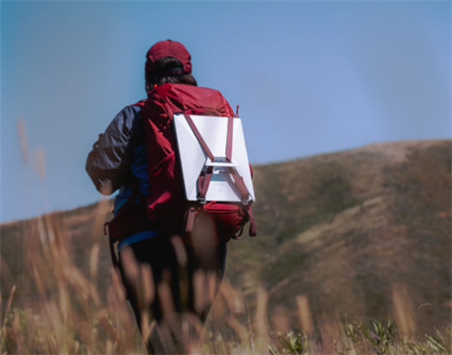 Backpacker hiking with a Starlink satellite dish mounted on their pack, bringing portable high-speed internet to the backcountry