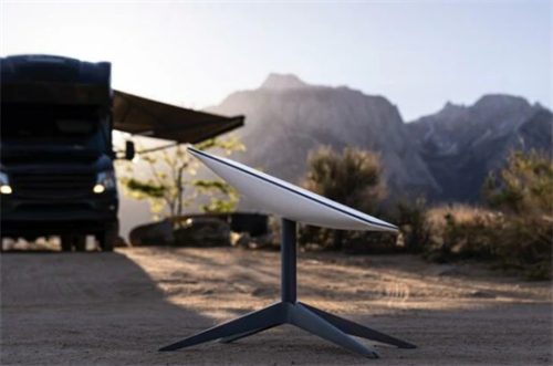 Starlink satellite dish set up at a desert campsite with an RV and mountains in the background, bringing high-speed internet to the wilderness