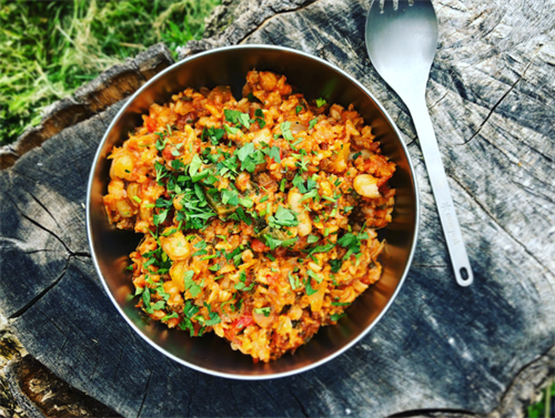 Classic backcountry one-pot meal of rice, beans, and herbs in a metal bowl, representing traditional trail cooking before 3D-printed food