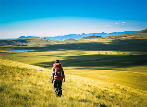 Solo hiker trekking across Lesotho’s vast golden grasslands in the Kingdom of the Sky