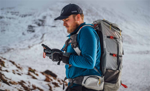 Hiker in snowy mountains using a smartphone or GPS device, relying on digital navigation instead of a mountain guide