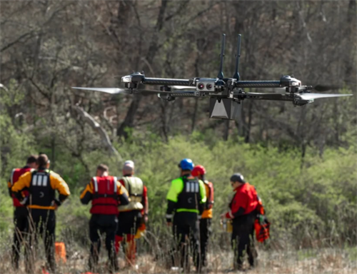 Search-and-rescue team observing an AI drone deployed for operations, demonstrating how drones assist ground teams in finding missing hikers