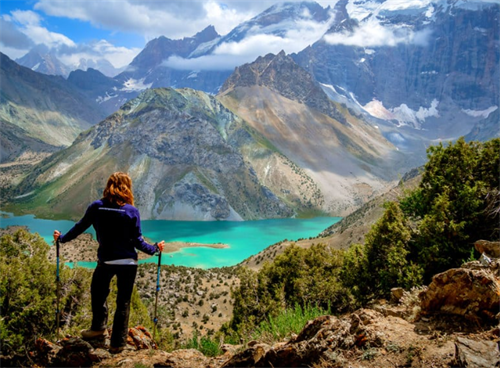 Female trekker admiring the turquoise alpine lakes and dramatic peaks of Tajikistan’s Fann Mountains