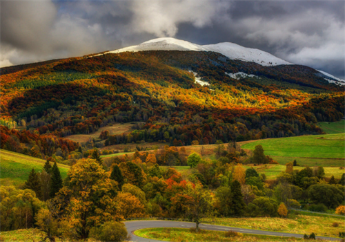 Autumn and winter meet in Bieszczady Mountains, Poland, with snow-capped peaks above fiery fall foliage