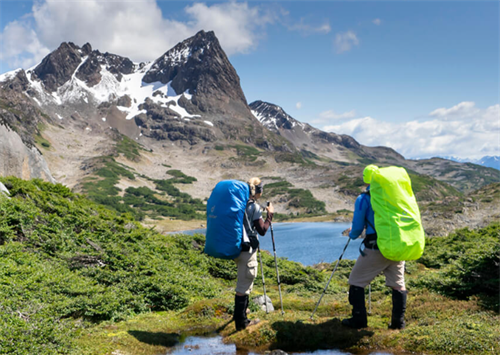 Two trekkers pausing to admire a turquoise lake and jagged mountains on the Dientes de Navarino Circuit at the end of the world
