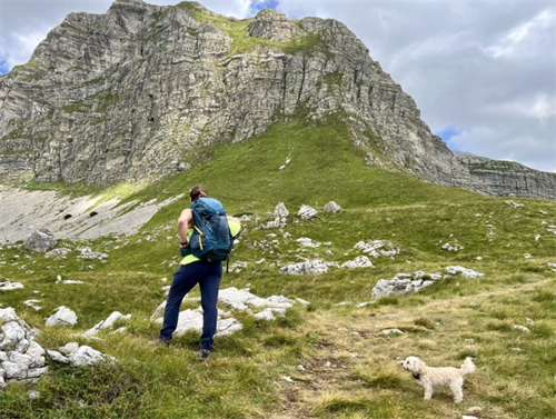Hiker with a small dog trekking toward a dramatic limestone peak in Durmitor National Park, Montenegro