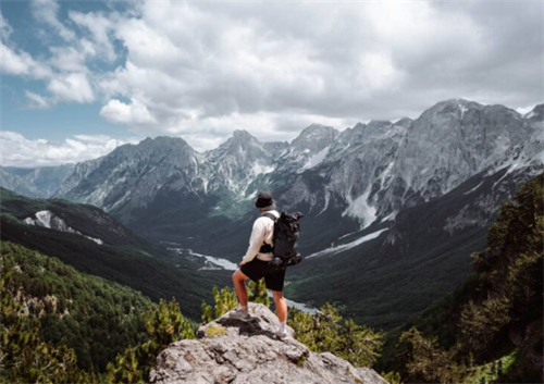 Solo trekker admiring the dramatic peaks of the Accursed Mountains from a viewpoint on the Valbona–Theth trail, Albania