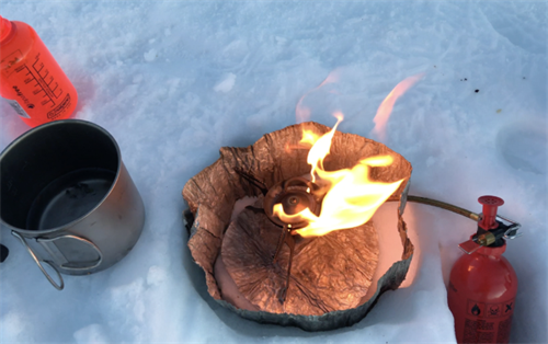 Liquid fuel stove burning efficiently in a snow shelter, demonstrating its performance in cold winter trekking conditions