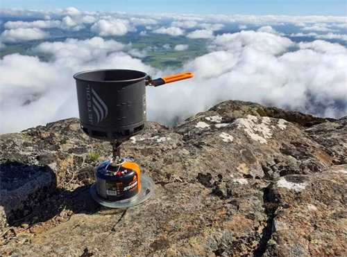 Jetboil canister stove system set up on a mountain summit above the clouds, ideal for high-altitude trekking